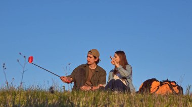Güneşli bir tarlada açık mavi gökyüzü ile selfie çekerken bir çift doğanın tadını çıkarıyor..