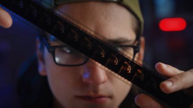 Şapka takan genç bir adam film şeridini yakından inceleyerek fotoğrafçılığa olan merak ve tutkuyu vurguluyor..