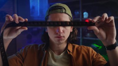 Şapka takan genç bir adam bir film şeridini yakından inceleyerek fotoğrafçılığa duyduğu merak ve tutkuyu vurguluyor. Yavaş çekim