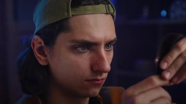 Şapka takan genç bir adam bir film şeridini yakından inceleyerek fotoğrafçılığa duyduğu merak ve tutkuyu vurguluyor. Yavaş çekim