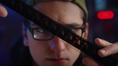 Şapka takan genç bir adam bir film şeridini yakından inceleyerek fotoğrafçılığa duyduğu merak ve tutkuyu vurguluyor. Yavaş çekim