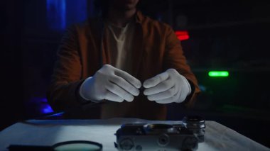 Eldiven giyen bir insan, loş bir fotoğraf stüdyosundaki film şeridini dikkatle tutar ve hassasiyeti vurgular. Yavaş çekim