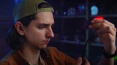 Genç bir adam loş bir odada bir film şeridini dikkatle inceliyor, film yapımında odaklanma ve merak öneriyor..