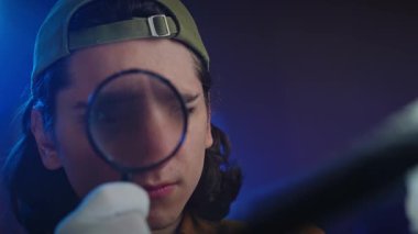 Büyüteçle incelenen eski bir film şeridinin yakından görüntüsü. Film analizinin ve korunmanın özünü yakalar. Kapat.