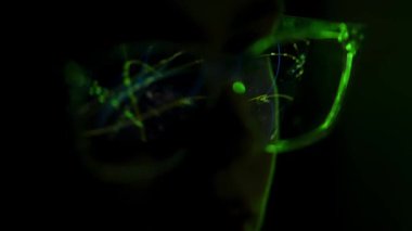 Parlak yeşil dijital desenleri yansıtan gözlükleri kapatın, loş bir ortamda veri analizini ve teknolojiyi sembolize edin..