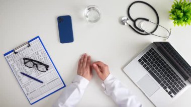 Sağlık sektörü çalışanlarının çalışma alanlarına genel bir bakış, temel tıbbi ekipman, belgeler ve teknolojinin düzenli beyaz bir masada yer alması. Üst çekim