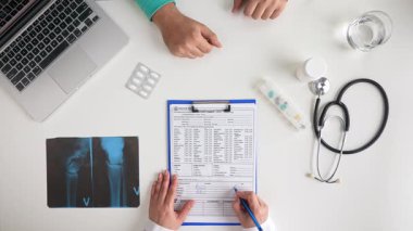 Bir sağlık uzmanı hasta muayenesi sırasında tıbbi kayıtları ve röntgenleri inceleyerek klinik muayeneyi açıklar. Üst çekim