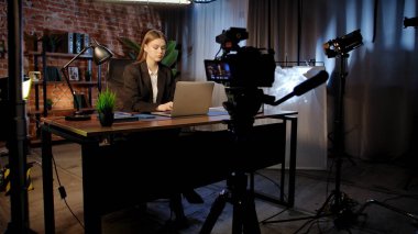 Sahne arkasında. Odaklanmış bir iş kadını masasında strateji düşünüyor. Ofis modern, dizüstü bilgisayarı ve düzgün düzenlenmiş belgeleri var..