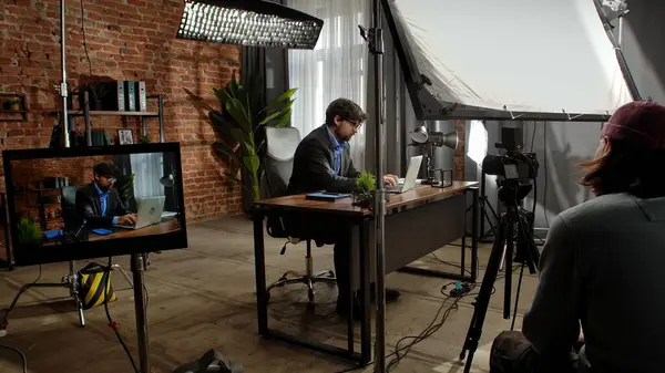 Sahne arkasında. Takım elbiseli bir işadamı, modern ofis ortamında tuğla duvarlar ve dekorlarla dizüstü bilgisayarına odaklanmıştı..