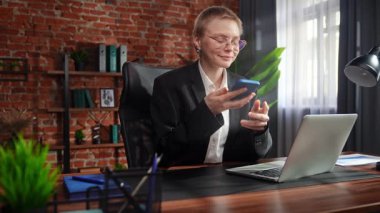 Kendini işine adamış bir birey, modern ofis ortamında telefonla konuşurken görülüyor. Konsantrasyon ve verimliliği vurguluyor..