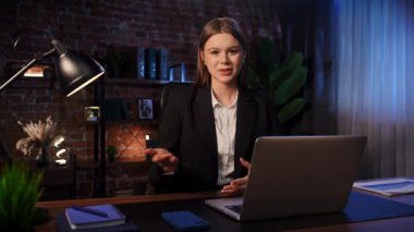 Odaklanmış bir iş kadını masasında strateji düşünüyor. Ofis modern, dizüstü bilgisayarı ve düzgün düzenlenmiş belgeleri var..