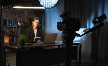 Sahne arkasında. Kendini işine adamış bir birey, modern ofis ortamında bir masaya notlar yazarken görülüyor. Konsantrasyon ve verimliliği vurguluyor..