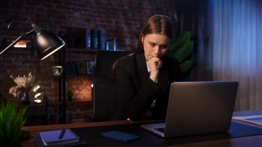 Modern ofis ortamındaki profesyonel bir kadın, geç saatlerde bilgisayarındaki işine çok önem verir..