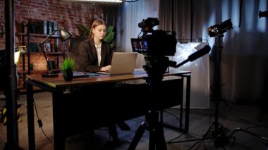 Sahne arkasında. Odaklanmış bir iş kadını masasında strateji düşünüyor. Ofis modern, dizüstü bilgisayarı ve düzgün düzenlenmiş belgeleri var..