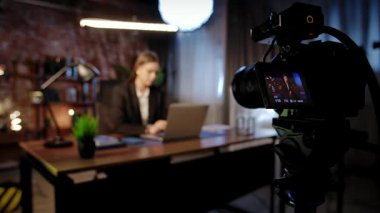 Sahne arkasında. Odaklanmış bir iş kadını masasında strateji düşünüyor. Ofis modern, dizüstü bilgisayarı ve düzgün düzenlenmiş belgeleri var..