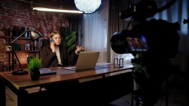 Sahne arkasında. Odaklanmış bir iş kadını masasında strateji düşünüyor. Ofis modern, dizüstü bilgisayarı ve düzgün düzenlenmiş belgeleri var..