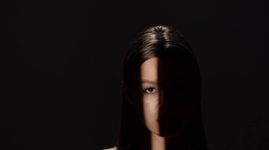 Yüzünün yarısı ışık huzmesi ve derin gölgelerle aydınlatılmış çarpıcı bir yan profil portresi..