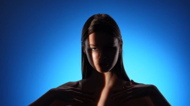 Görsel olarak büyüleyici bir portre dramatik ışıklandırma içinde bir kadını canlı mavi arka planda gösteriyor..