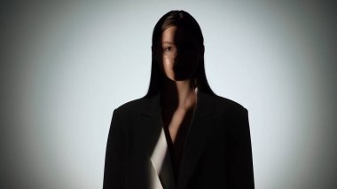 Çarpıcı bir portre dramatik ışıklandırmayla bir yüzünü gölgede bırakan bir kadın, gizemli bir etki yaratıyor..