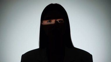 Çarpıcı bir portre dramatik ışıklandırmayla bir yüzünü gölgede bırakan bir kadın, gizemli bir etki yaratıyor..