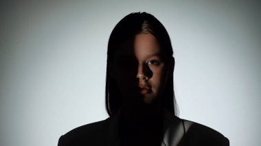 Çarpıcı bir portre dramatik ışıklandırmayla bir yüzünü gölgede bırakan bir kadın, gizemli bir etki yaratıyor..