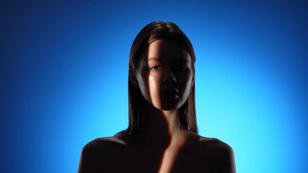 A visually captivating portrait showcasing a woman in dramatic lighting against a vivid blue background.