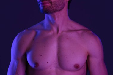 Bir erkek gövdesi mavi ve mor ışığın sanatsal bir karışımıyla vurgulanır ve dramatik bir görsel etki yaratır..