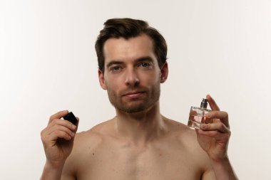 Beyaz arka planla işaretlenmiş bir parfüm şişesine bakan bir adam zarafet ve entelektüellik taşıyor..