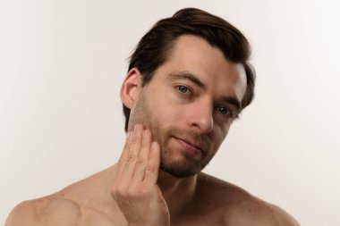 Düşünceli bir ifade sergileyen bir adamın portresi. Kısa saçları ve bir küpesi var. Benzersiz tarzının altını çiziyor..