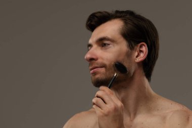 Bir adam alnında siyah yeşim bir silindir kullanıyor. Cilt bakımının bir parçası olarak yüz gençleştirme için..