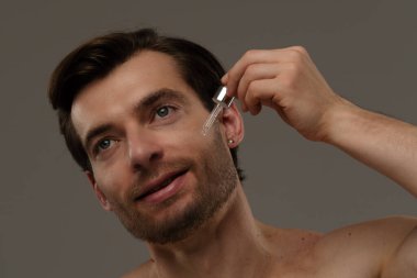 Bir erkek, deri dokusunu geliştirmek ve beslenmek için deri serumunu nazikçe kullanır..