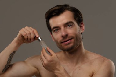 Bir erkek, deri dokusunu geliştirmek ve beslenmek için deri serumunu nazikçe kullanır..