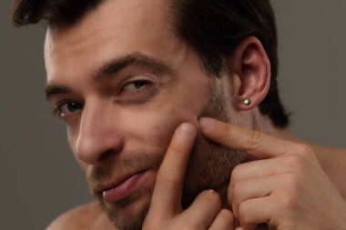 Rahatlamış ve kendine güveni tam bir adam yüzüne dokunuyor, rahat ve dostane bir tavır sergiliyor..