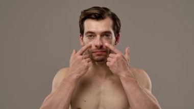 Düşünceli bir ifade sergileyen bir adamın portresi. Kısa saçı ve eşsiz tarzının altını çizen bir küpesi var. Yavaş çekim