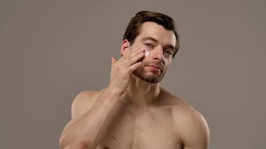 Düşünceli bir ifade sergileyen bir adamın portresi. Kısa saçı ve eşsiz tarzının altını çizen bir küpesi var. Yavaş çekim