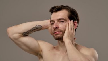 Rahatlamış ve kendine güvenen bir adam kameraya gülümserken saçına dokunur, rahat ve arkadaş canlısı bir tavır sergiler. Yavaş çekim