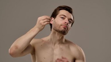 Bir adam deri dokusunu geliştirmek ve beslenmek için deri serumunu nazikçe kullanır. Yavaş çekim