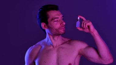 Bir adam deri dokusunu geliştirmek ve beslenmek için deri serumunu nazikçe kullanır. Yavaş çekim