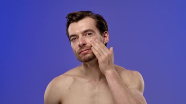 Cilt kremi kavanozuna odaklanmış bir yüz ifadesini inceleyen bir adam, muhtemelen cildine olan faydalarını göz önünde bulundurur. Yavaş çekim