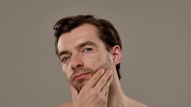 Düşünceli bir ifade sergileyen bir adamın portresi. Kısa saçı ve eşsiz tarzının altını çizen bir küpesi var. Yavaş çekim