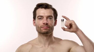 Bir adam deri dokusunu geliştirmek ve beslenmek için deri serumunu nazikçe kullanır. Yavaş çekim