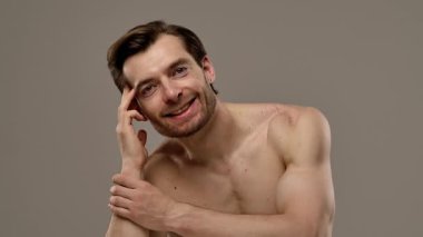 Rahatlamış ve kendine güvenen bir adam kameraya gülümserken saçına dokunur, rahat ve arkadaş canlısı bir tavır sergiler. Yavaş çekim