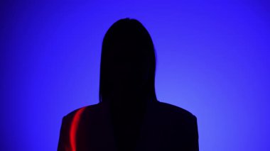 Bir insan dramatik bir ışığa yakalanıyor, canlı mavi ve kırmızı gölgeler içeriyor, gizemli ve ilgi çekici bir görsel etki yaratıyor..