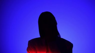 Bir insan dramatik bir ışığa yakalanıyor, canlı mavi ve kırmızı gölgeler içeriyor, gizemli ve ilgi çekici bir görsel etki yaratıyor..