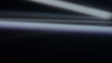 Karanlık bir arkaplanda ilerleyen parlak ışık demetlerinin yer aldığı soyut bir görüntü, fütüristik ve dinamik bir görsel efekt yaratır. Macro, ağır çekim.