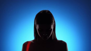 Bir insan dramatik bir ışığa yakalanıyor, canlı mavi ve kırmızı gölgeler içeriyor, gizemli ve ilgi çekici bir görsel etki yaratıyor..