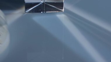 Işığı yansıtan ve kıran, soyut desenler ve ince renk değişimleri yaratan bir prizmanın görüntüsü. Macro, ağır çekim.