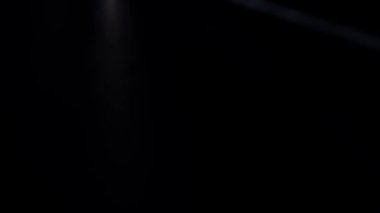 Karanlık bir arkaplanda ilerleyen parlak ışık demetlerinin yer aldığı soyut bir görüntü, fütüristik ve dinamik bir görsel efekt yaratır. Macro, ağır çekim.