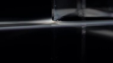 Büyüleyici bir görüntü cam prizma ile ışığın etkileşimini yakalıyor, çarpıcı kırılma desenleri sergiliyor. Macro, ağır çekim.
