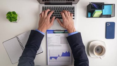 Bir dizüstü bilgisayar, ekonomi grafikleri, bir defter ve bir kahve fincanının yer aldığı iş yerinin en üst görüntüsü. Üretkenlik için ideal. Üst çekim